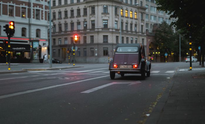 A vintage car driving through a city on a street 