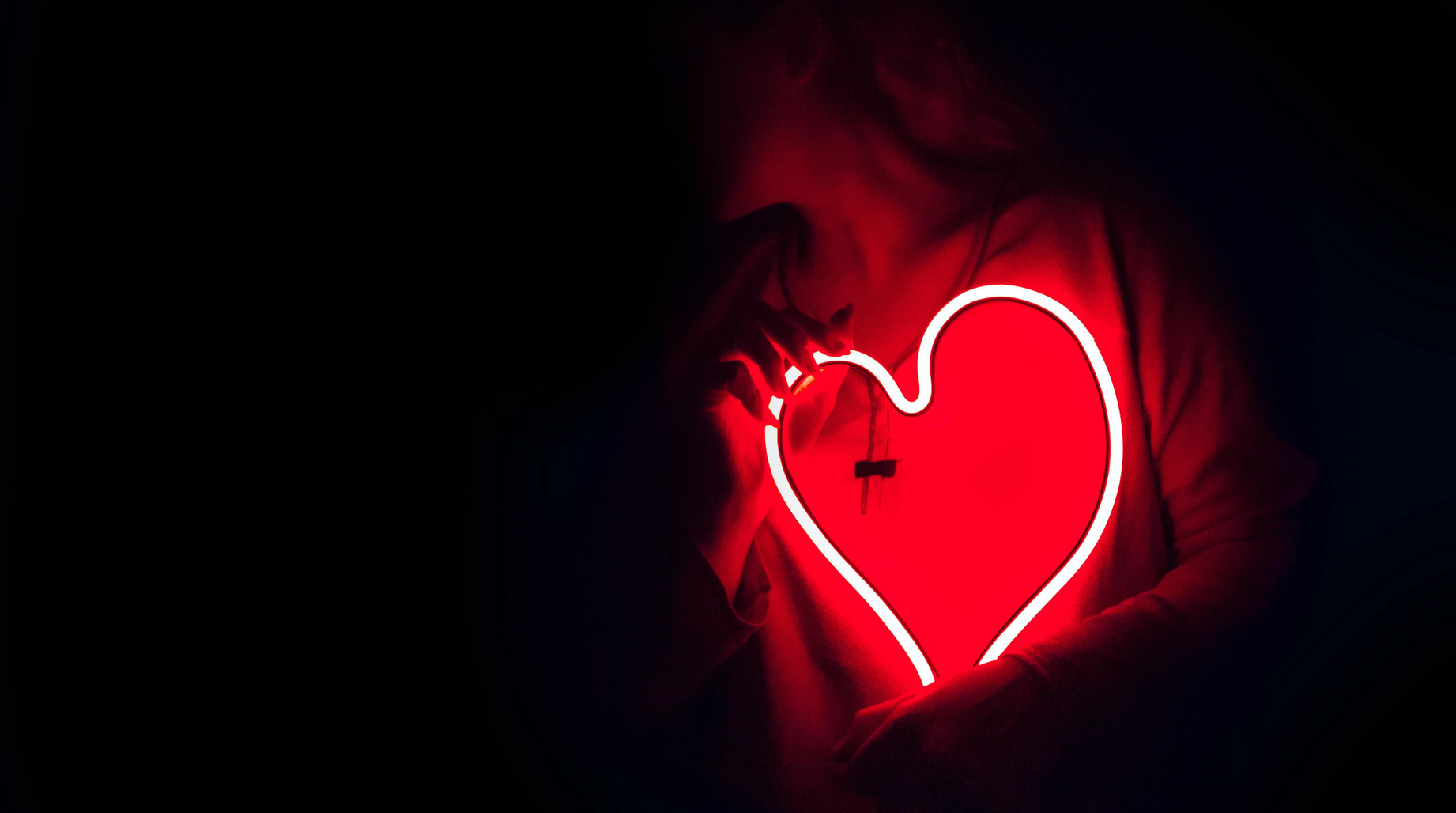 Personne qui tient un une lampe néon en forme de coeur
